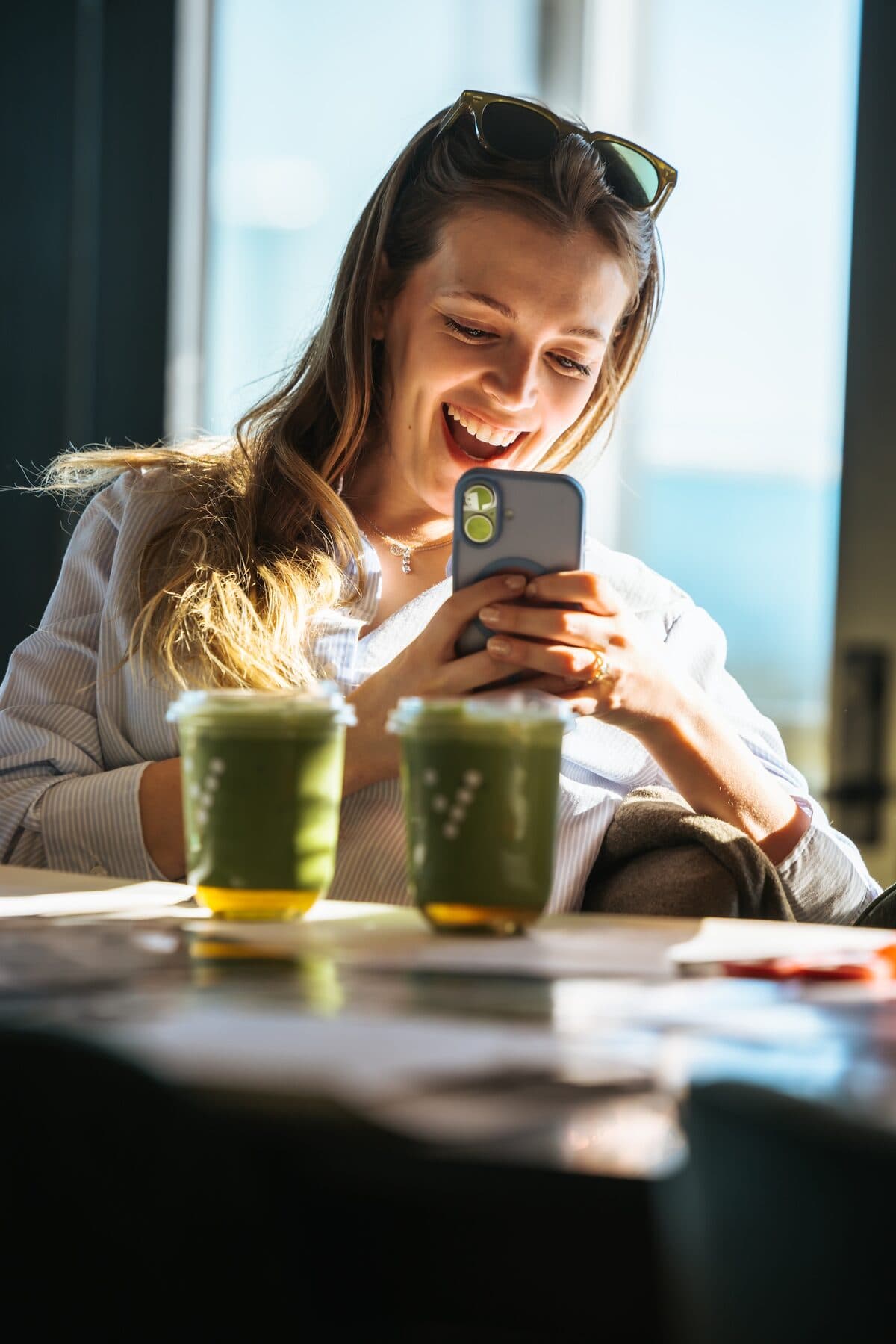 Vale ambassador laughing at her phone with two Vale matcha drinks on the table
