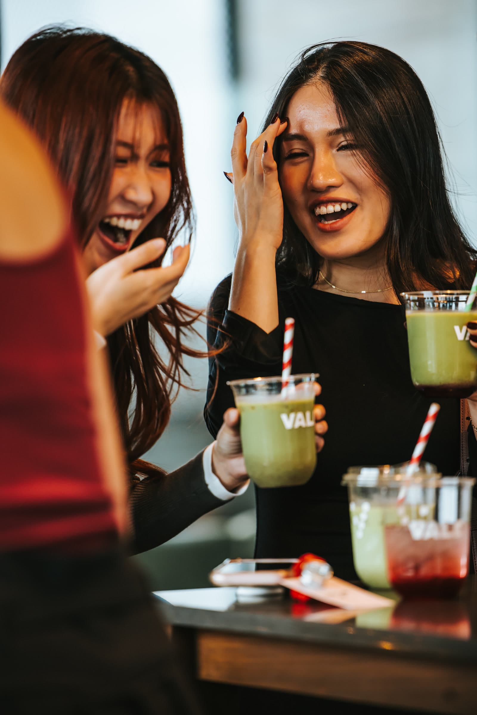 Friends laughing together with Vale matcha drinks at a brand activation