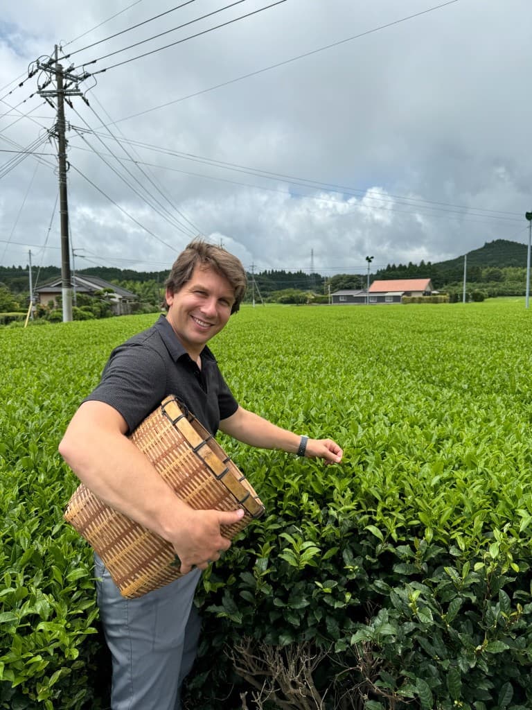 Vale founder Luke Larson hand-picking tea leaves with a bamboo basket in a Japanese tea field