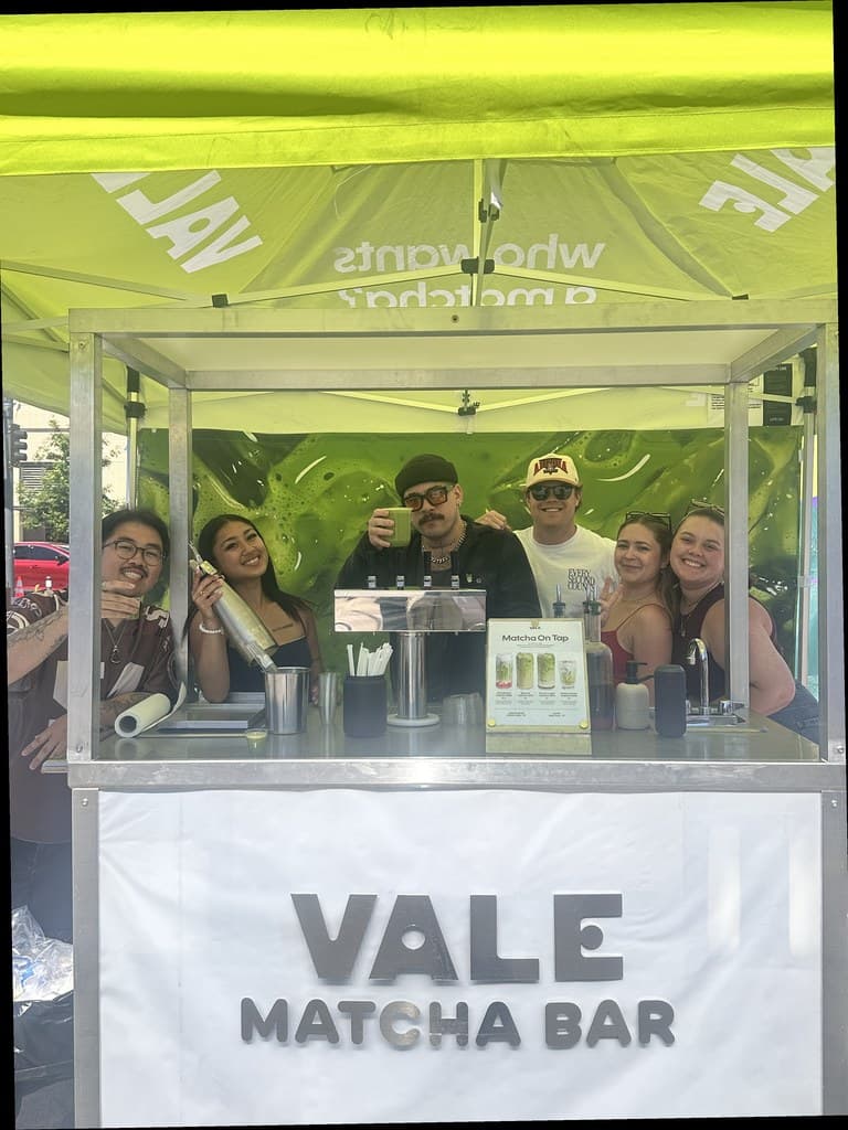 Vale team smiling behind the Matcha Bar cart under a lime canopy at Cal Anderson Park