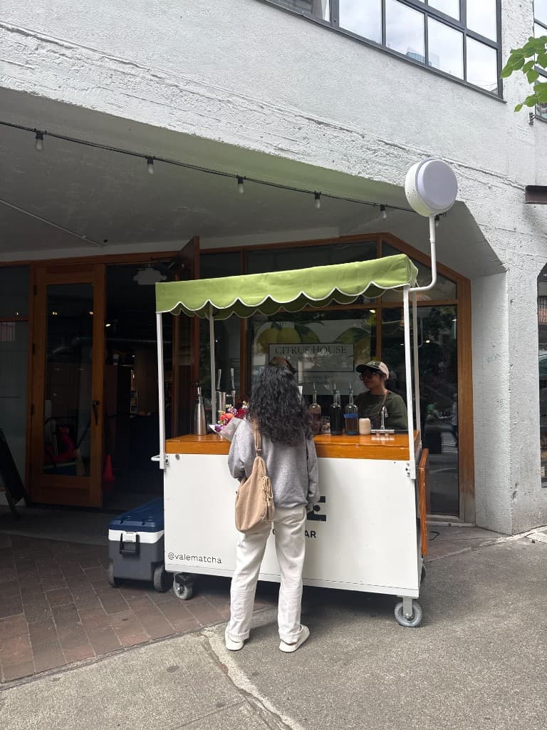 Vale Matcha Bar cart with a green scalloped canopy outside Citrus House on Western Ave near Pike Place Market in Seattle