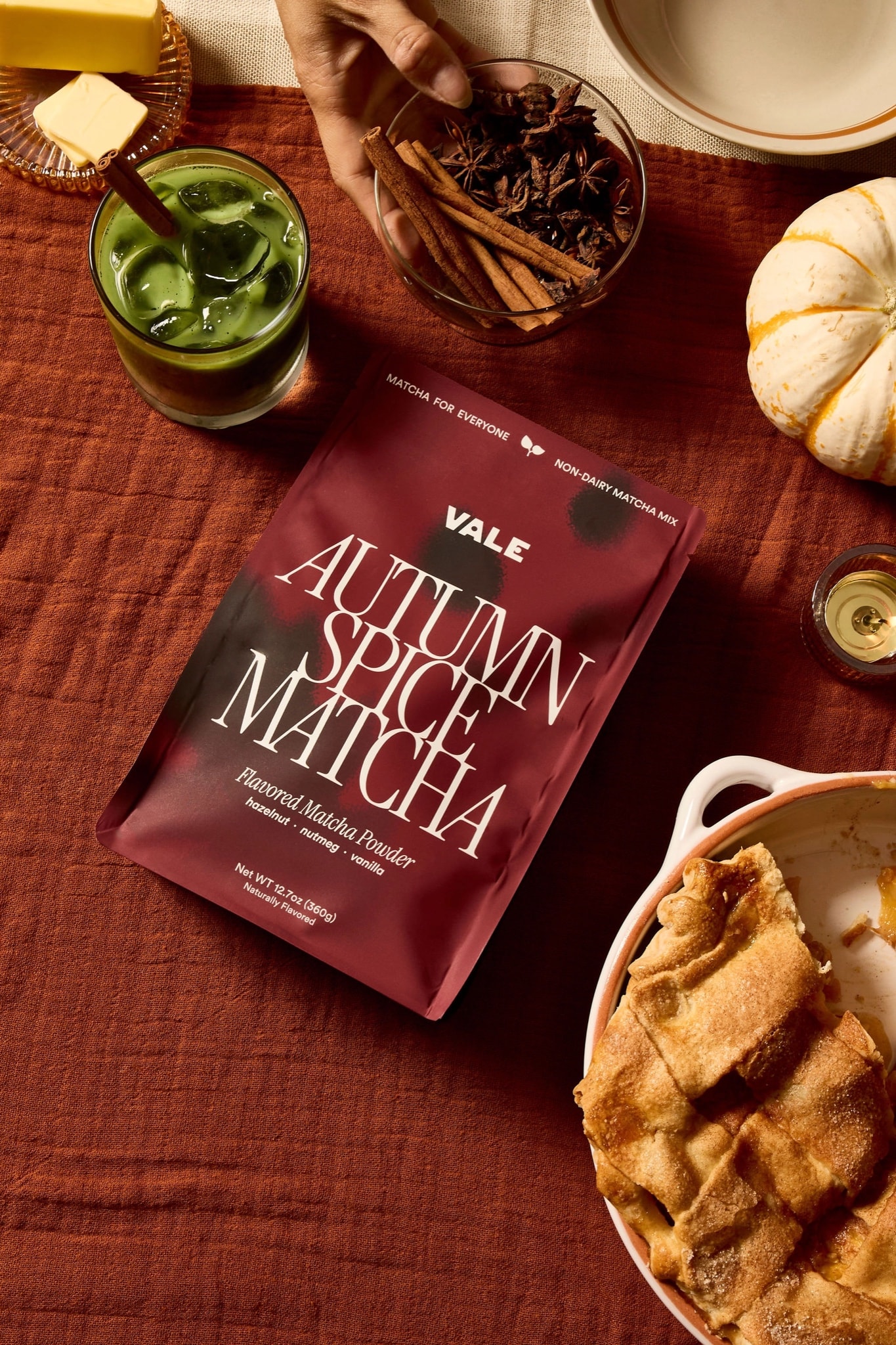 Autumn Spice Matcha bag on a fall table with spices, iced matcha, and pie