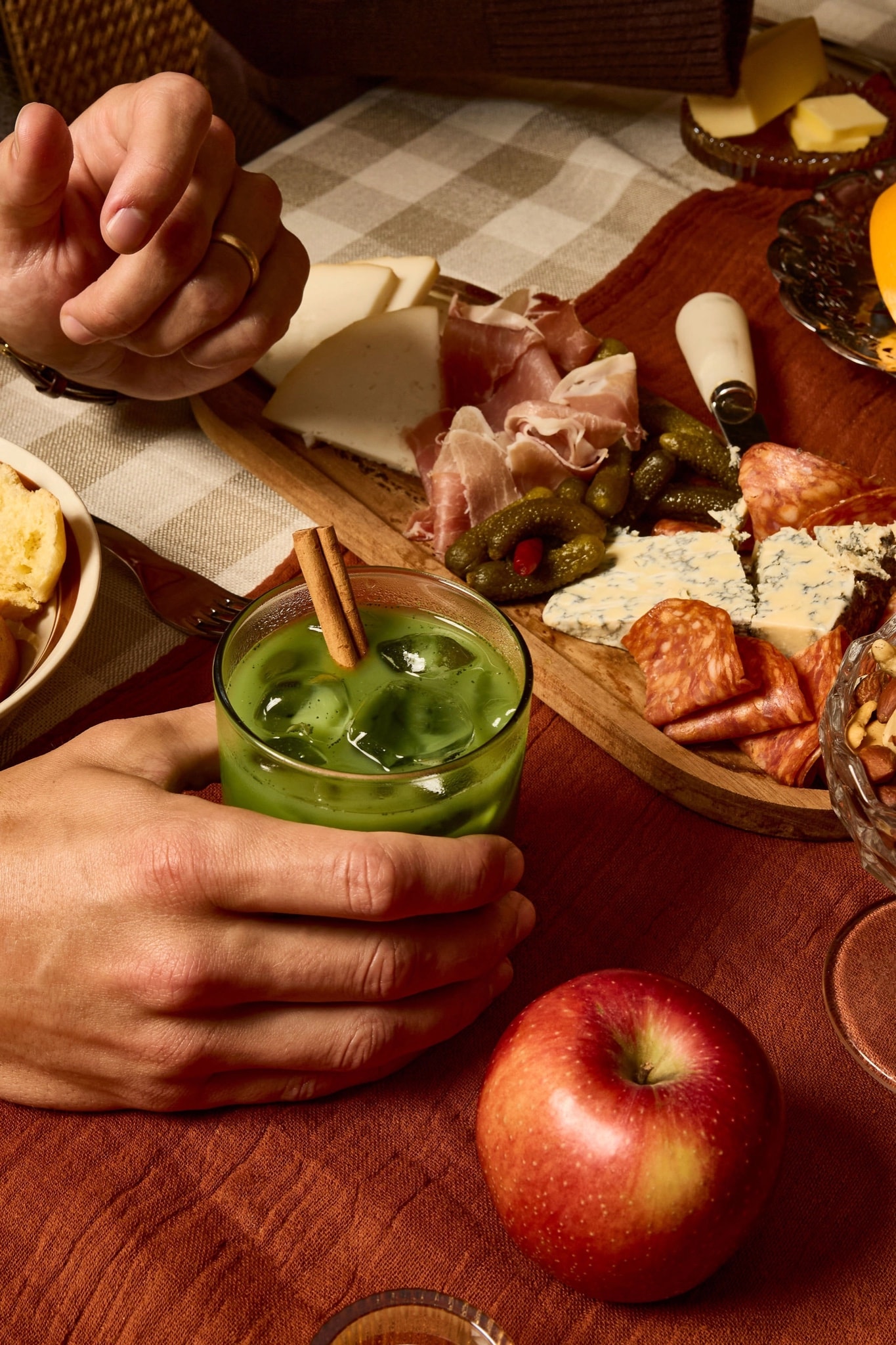 Iced Autumn Spice Matcha in hand beside a fall charcuterie board