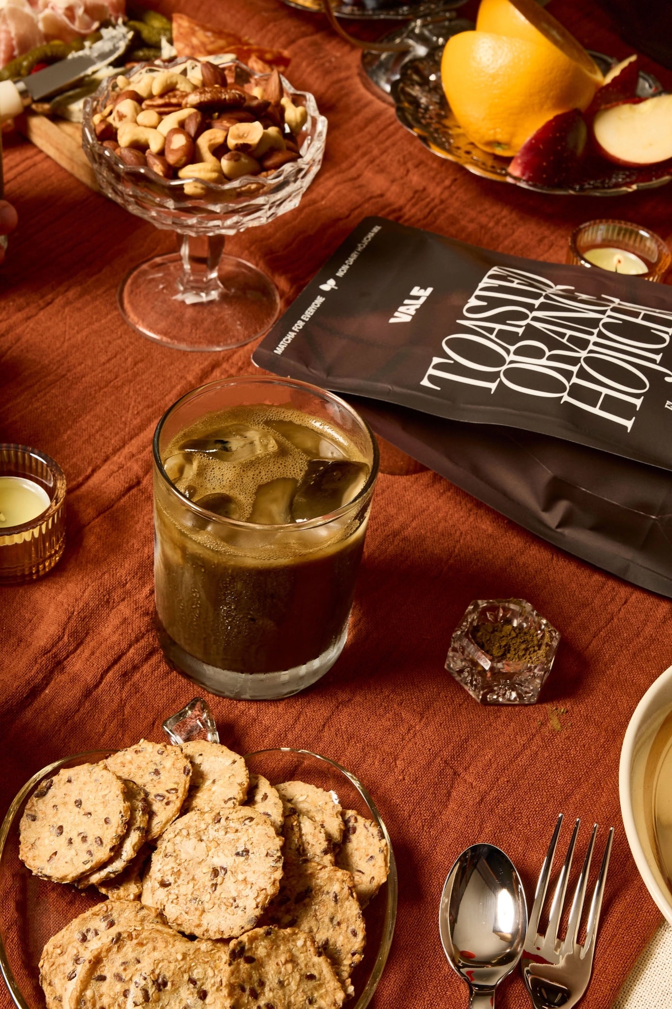 Toasted Orange Hōjicha bag and iced latte on a Friendsgiving table
