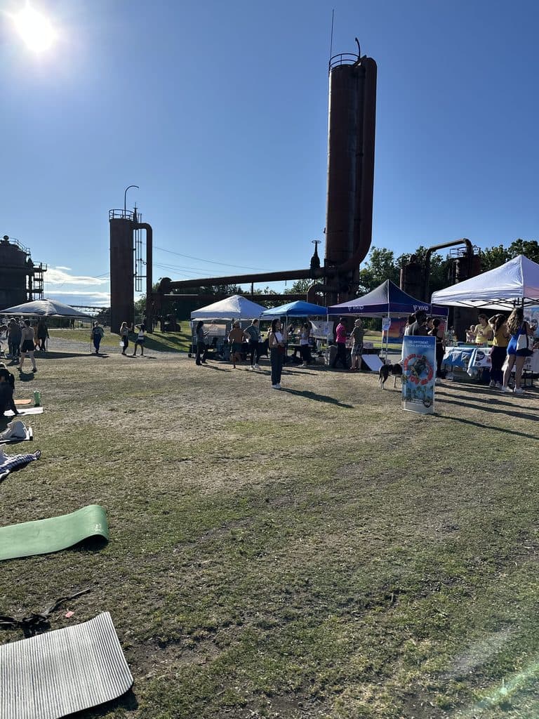 Yoga mats and vendor tents at Gas Works Park in Seattle during Yoga in the Park, with the historic gas works towers behind them