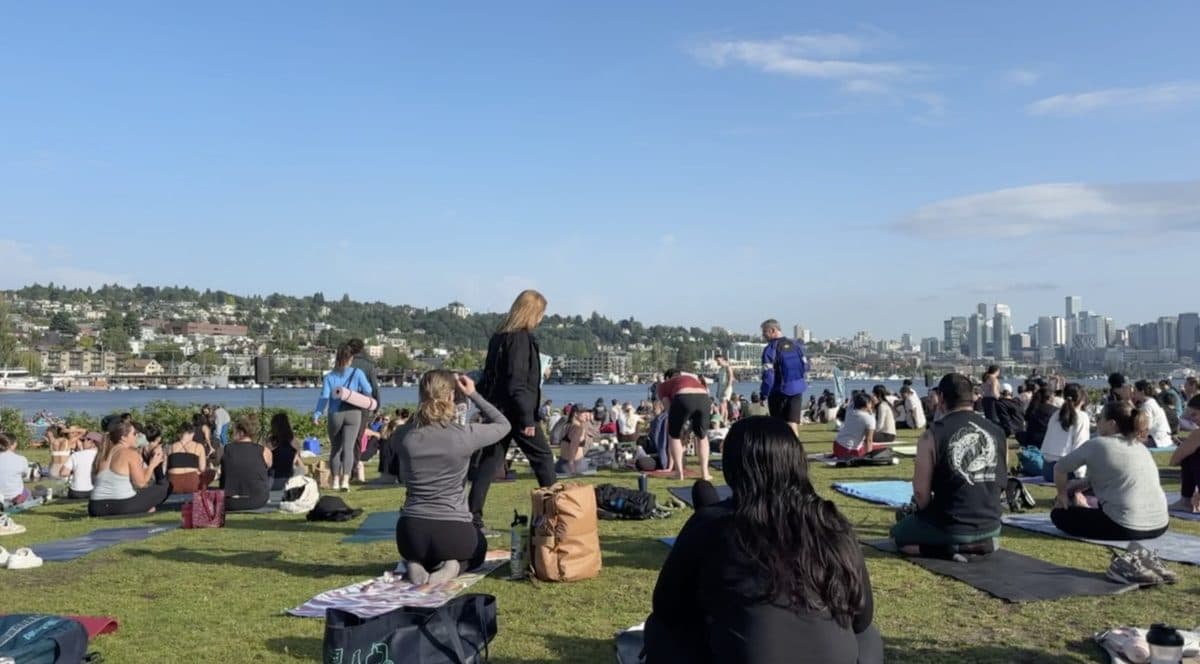 Crowds on yoga mats at Yoga in the Park overlooking Lake Union and the Seattle skyline from Gas Works Park