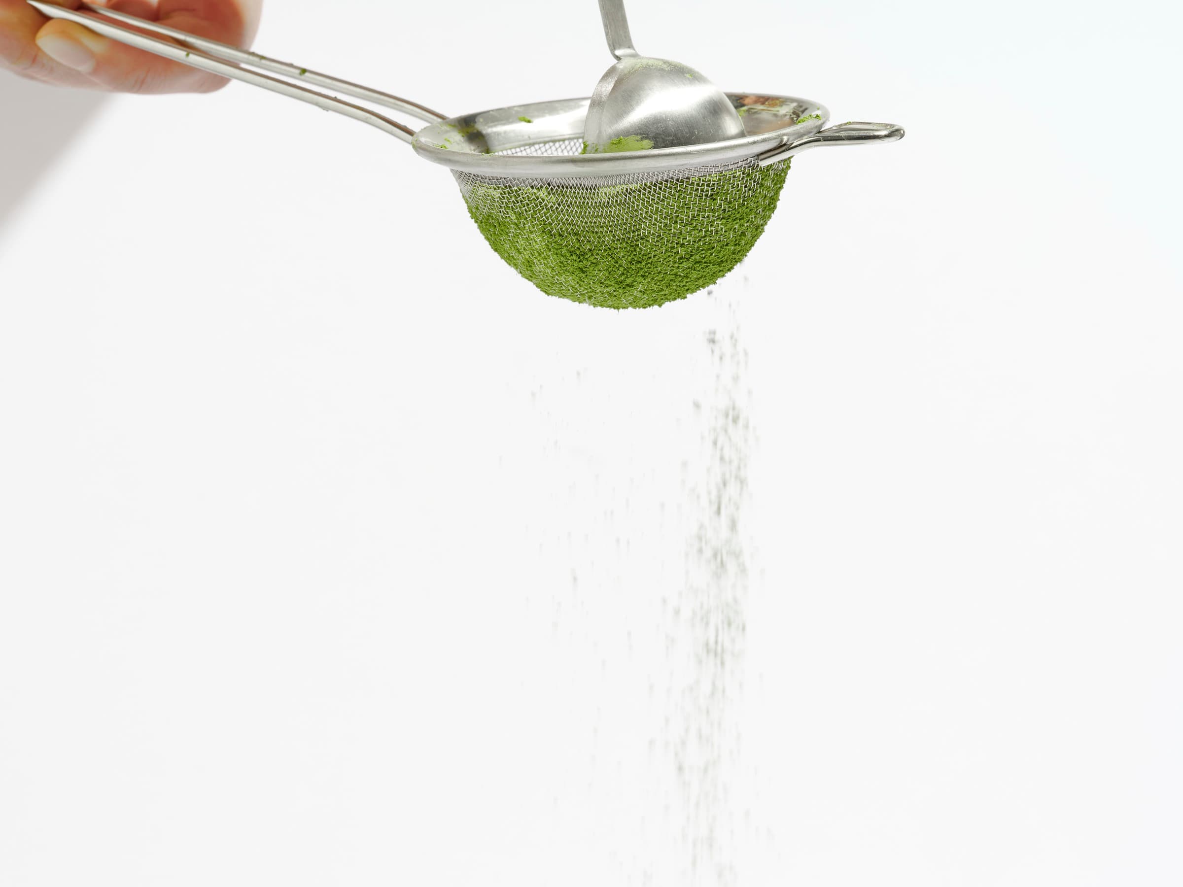Matcha being sifted through a fine mesh strainer
