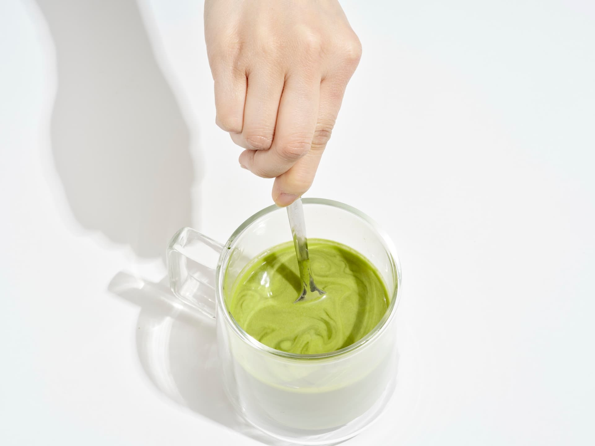 Stirring freshly made matcha in a glass mug