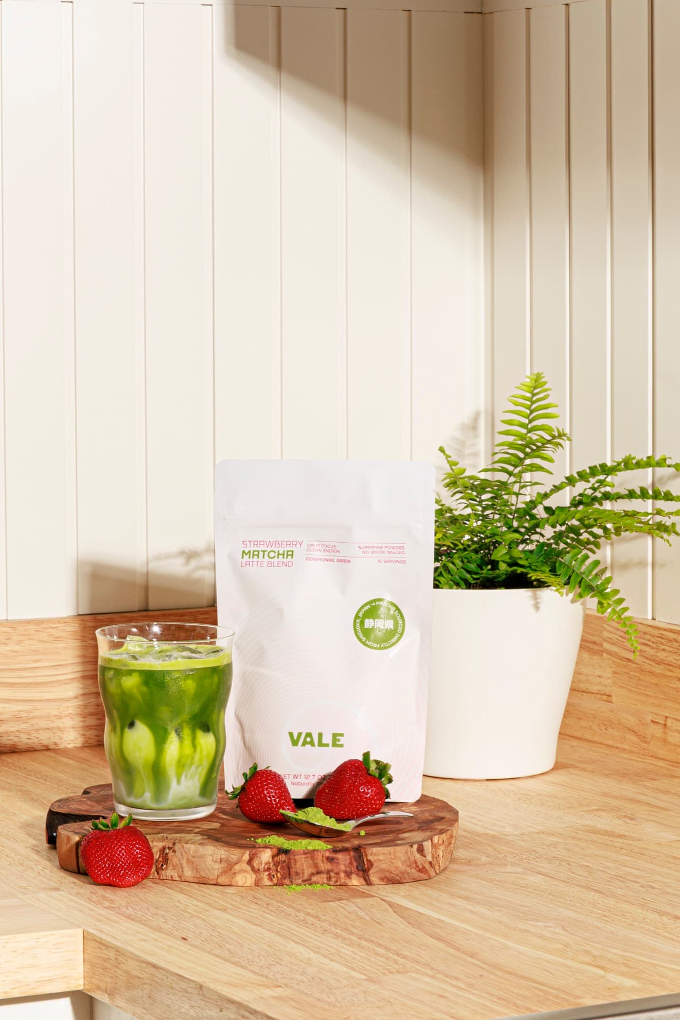 Strawberry Matcha Latte with fresh strawberries on a wooden cutting board