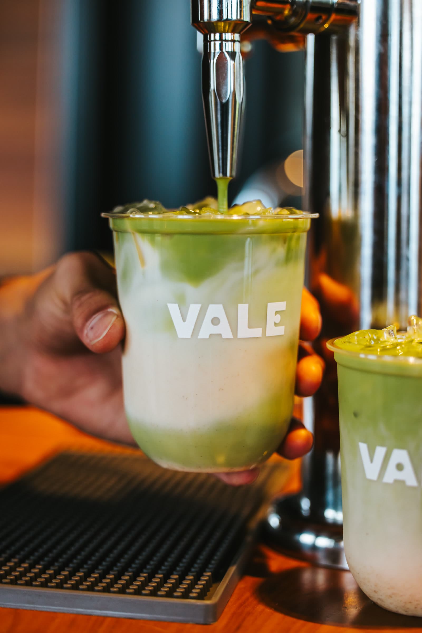 Vale matcha on tap pouring into a VALE-branded cup
