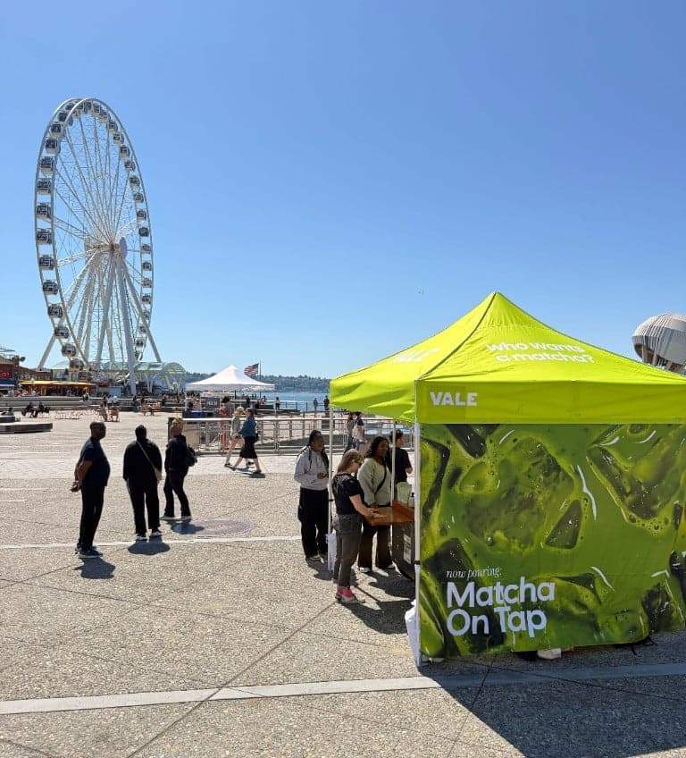 Vale Matcha Bar canopy at Waterfront Park on Alaskan Way, with the Seattle Great Wheel and Elliott Bay behind it