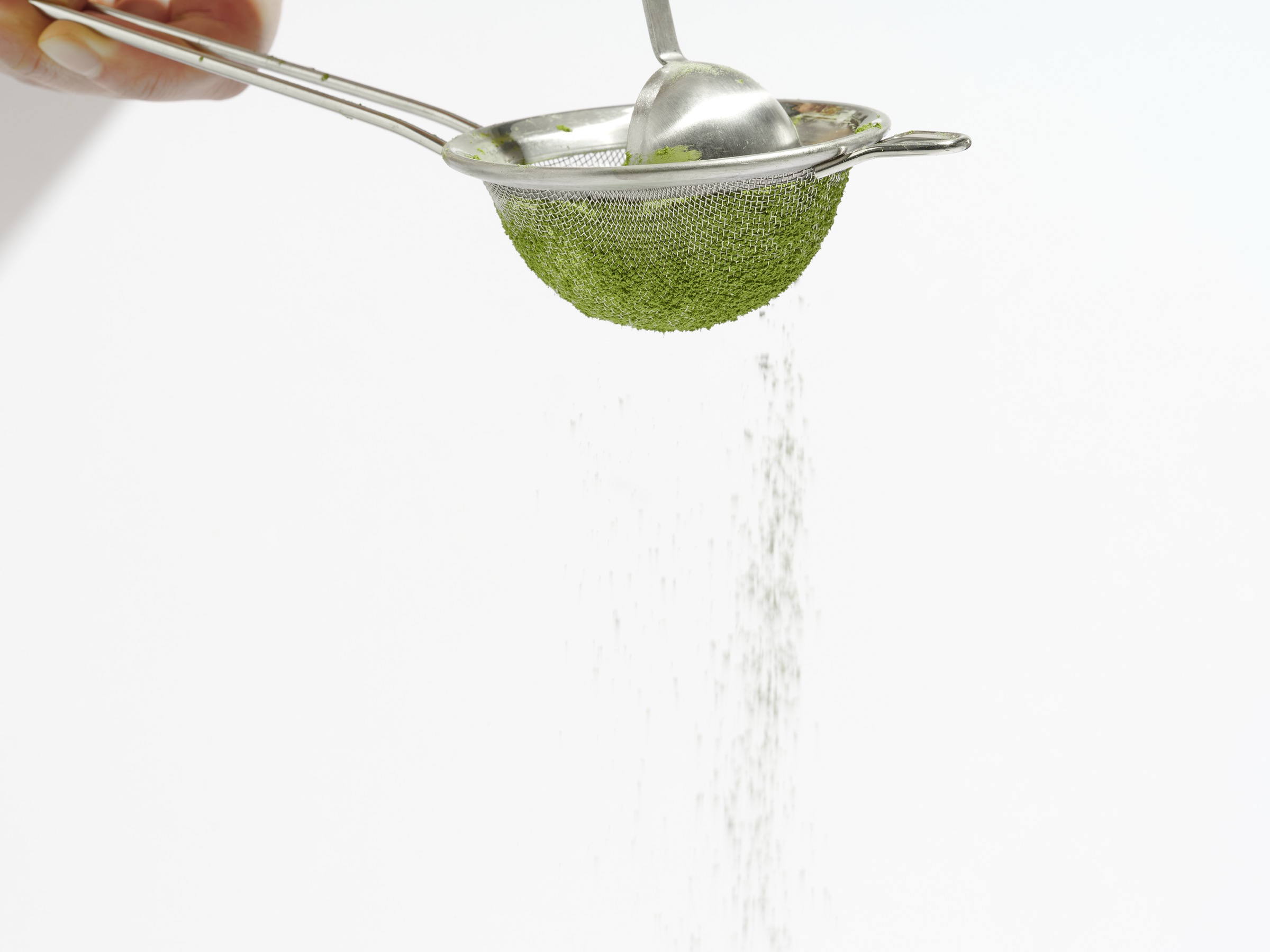 Matcha being sifted through a fine mesh strainer