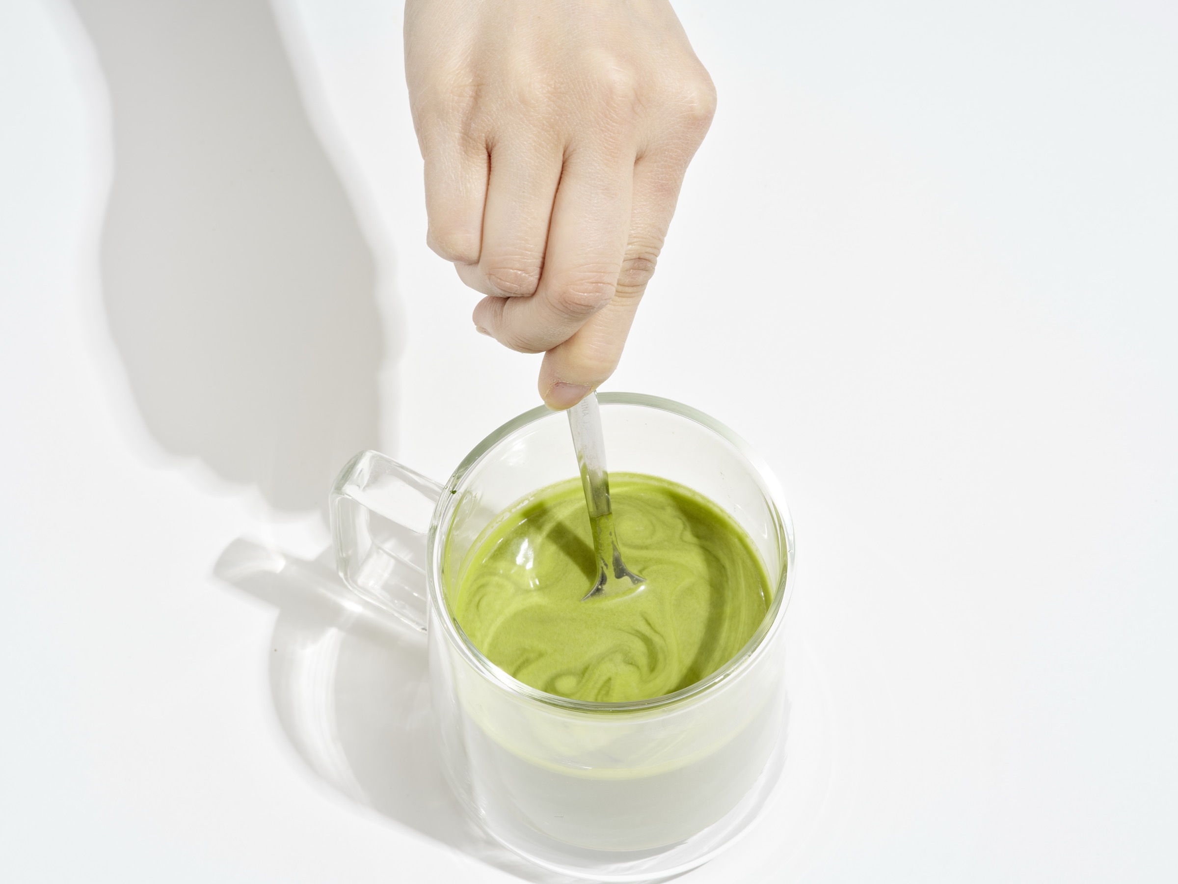 Stirring freshly made matcha in a glass mug
